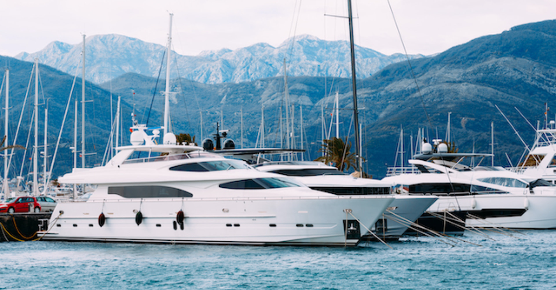 Why People Charter Explorer Yachts, multiple yachts docked near mountains.