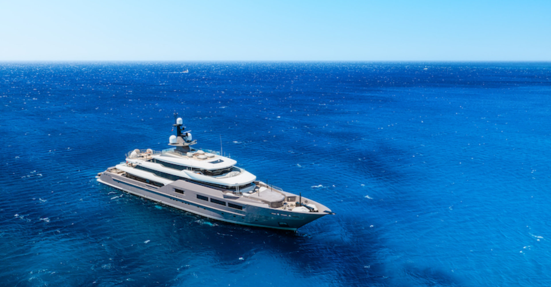 €1 Million Per Week Yacht Charter, large luxury yacht on blue waters.