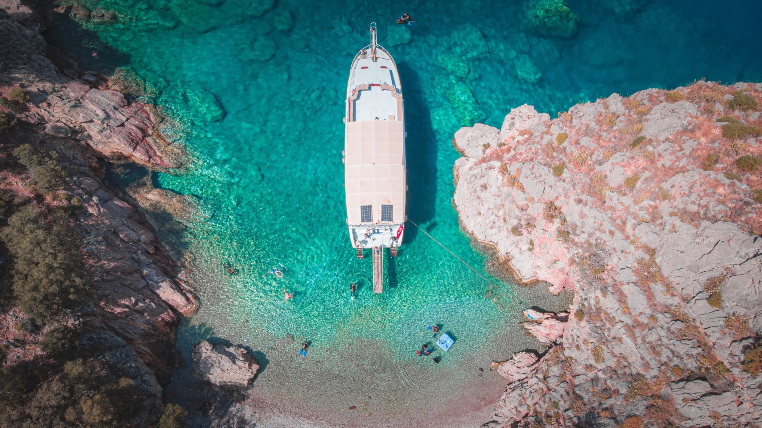 Choose Onboard Yacht Activities, yacht near shore with people swimming.